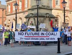 People standing in a town centre holding a banner which reads: " Nofuture in coal! We need climate jobs, not dole"