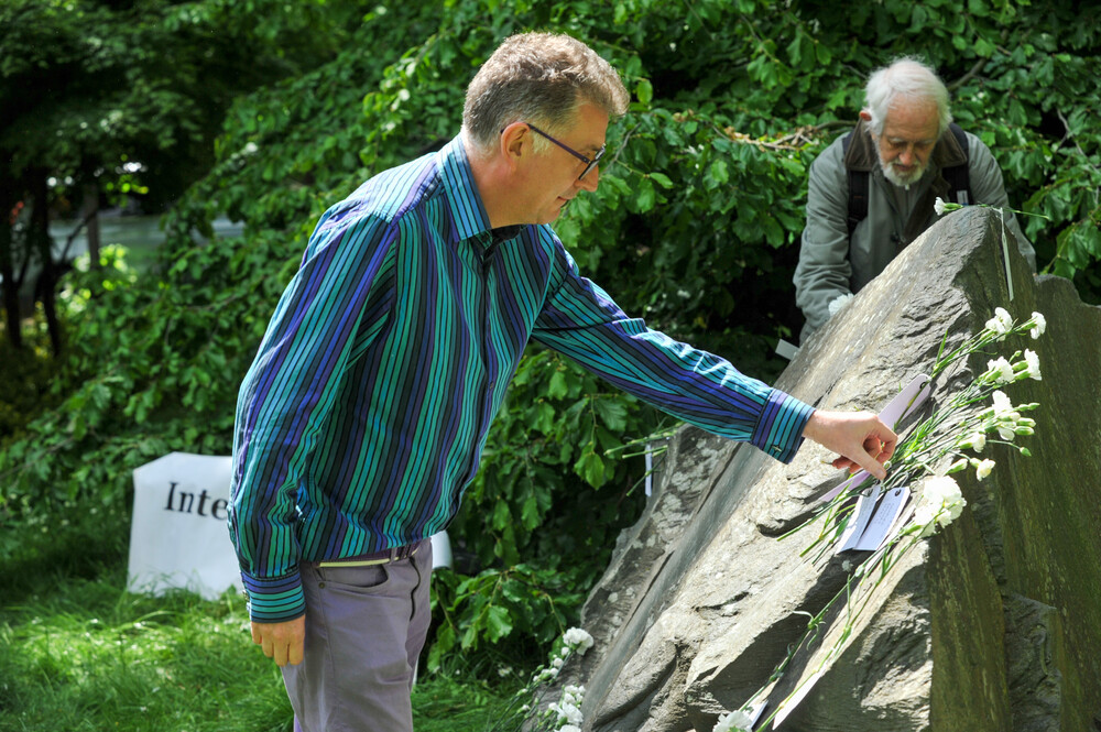 A man places a white carnation on the Conscientious Objectors' memorial stone in Tavistock Square, London, UK
