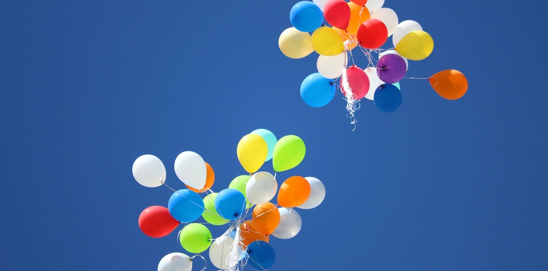 Bunches of coloured ballons floating up into a blue sky