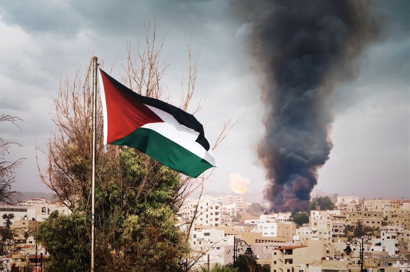 Palestinian flag against backdrop of burning city
