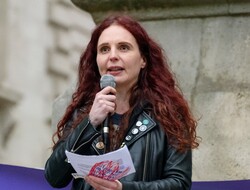 Two adults and a child standing by a banner outside the ExCel Centre in London. The banner reads 'Quakers for Climate Justice' 