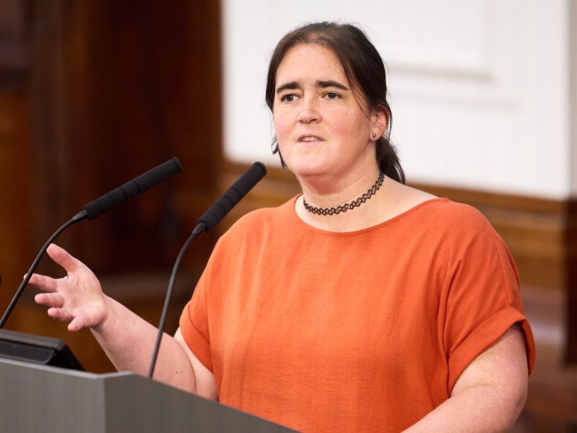 woman in orange shirt at lecturn