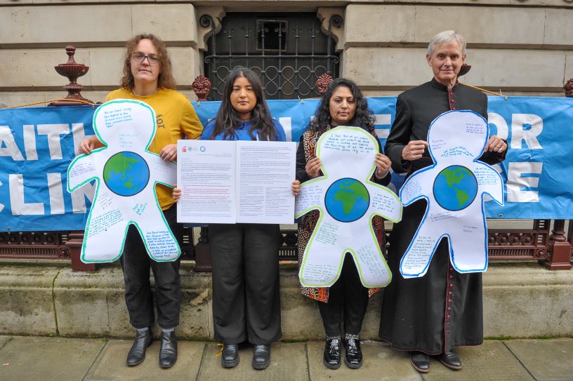 People holding cut out figures in front of building