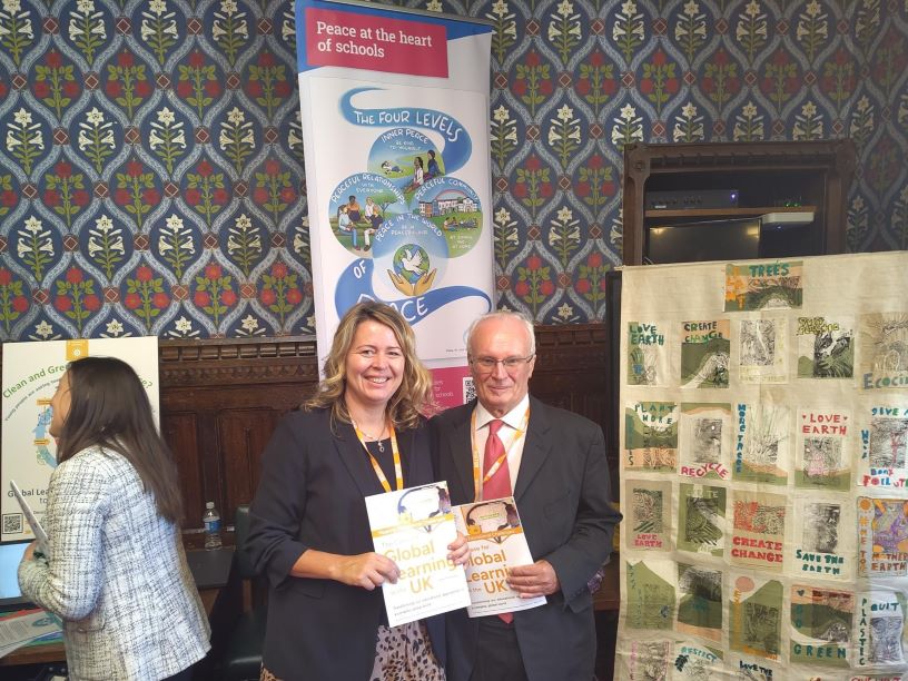 Two people holding a report standing in front of posters