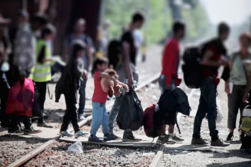 People carrying bags across railway track, faces blurred