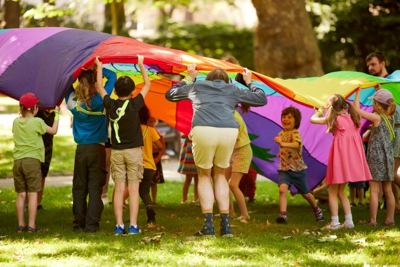 Children and an adult playing with a parachute