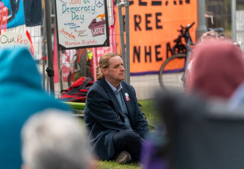 Man seated on ground in front of banners