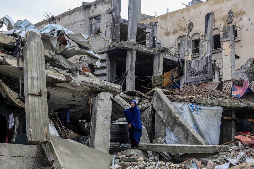 Woman in blue robe standing on destroyed buildings