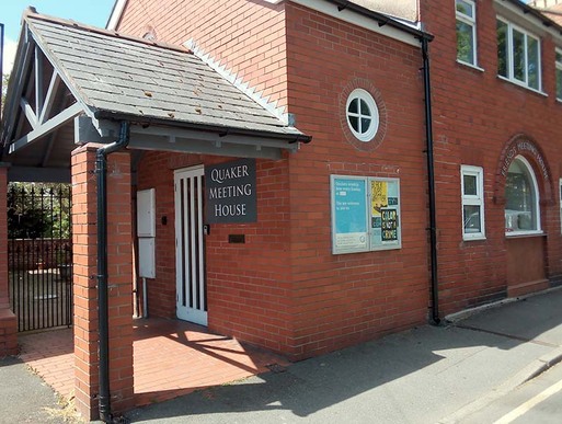 Red brick built simple house with conspicuous roof which in every part is lower than previous.